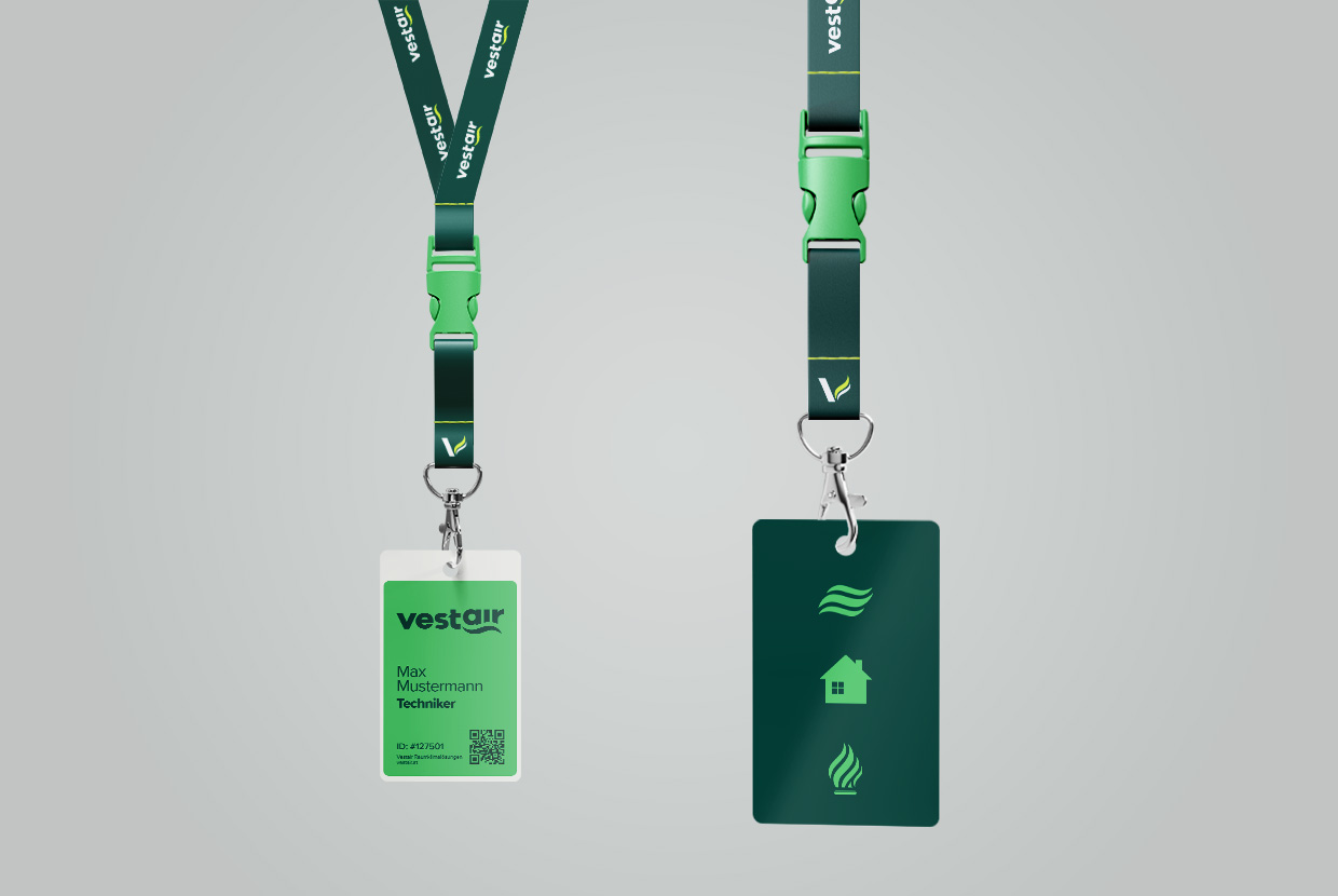 Zwei Vestair Keychains mit angehängten Vestair-Pässen, die das Logo und Icons zeigen