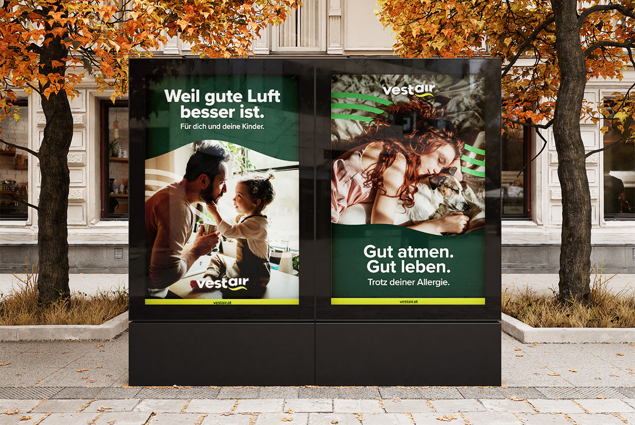 Zwei Vestair-Plakate in City Lights, die einen Vater und sein Kind oder eine Frau im Bett mit ihrem Hund zeigen samt Claims und Logo