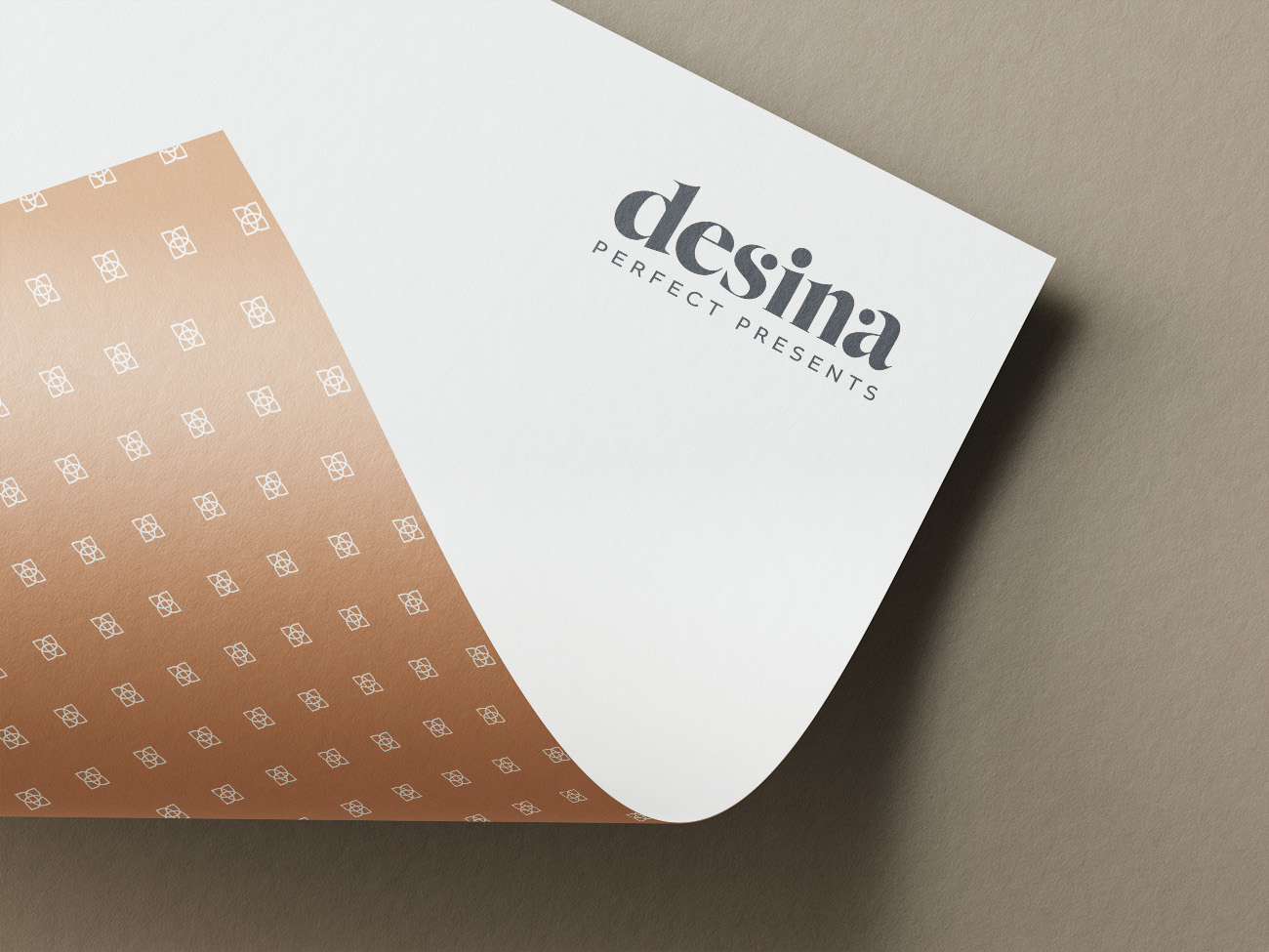 Antares Advertising - Projekt Desina - Mockup zeigt ein halb eingerolltes gebrandetes Briefpapier mit Logo auf der Vorderseite und Muster auf der Rückseite auf einer braunen Fläche