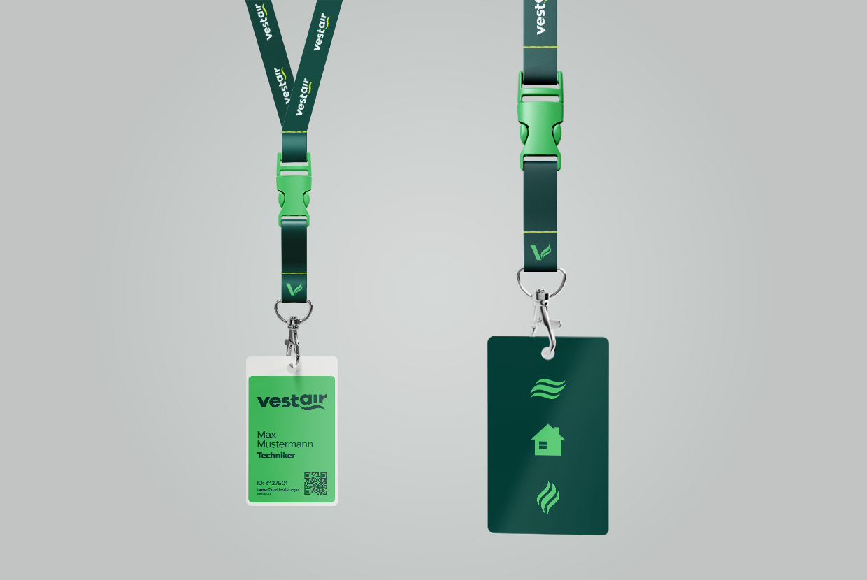 Zwei Vestair Keychains mit angehängten Vestair-Pässen, die das Logo und Icons zeigen